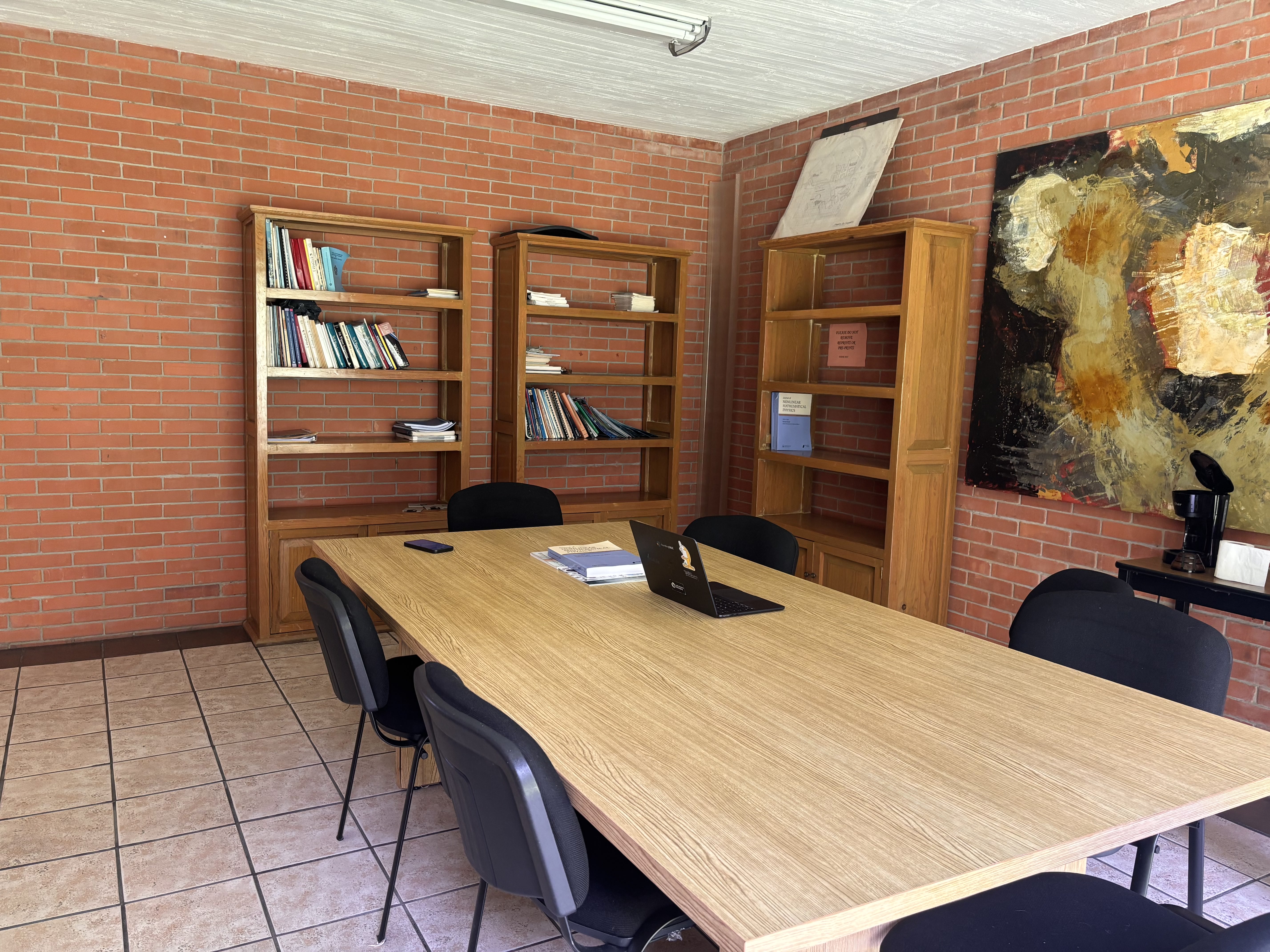 Sala de reuniones con mesa de trabajo, libreros y obra de arte